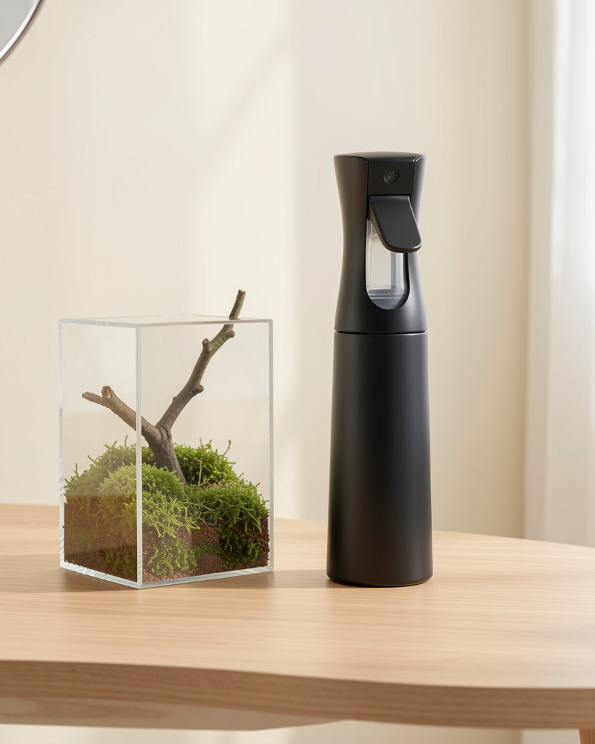 Black mist spray bottle on a desk next to a planted enclosure that is not included
